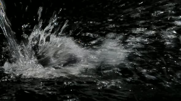 Vibrant Water Falling and Splashing on Dark Surface in Slow Motion. Amazing Shooting Close Up