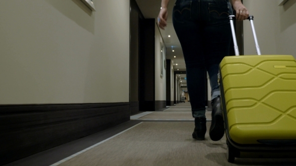 Woman With Trolley Bag Looking For Room In Hotel