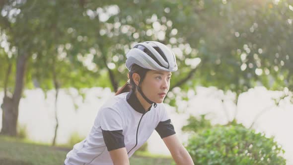 Asian young woman riding bicycle for health in evening at public park.