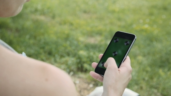 Pregnant Woman Using Mobile Phone In Park