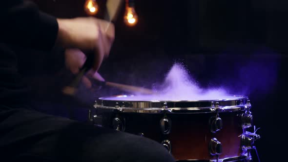 Drummer playing with sticks on a snare drum with smoke with beautiful lighting