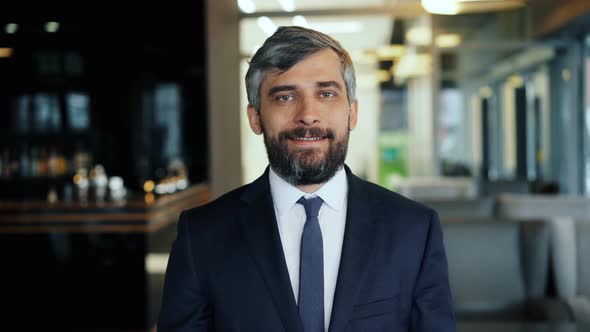 Portrait of Smiling Businessman in Suit Standing in Cafe Looking at Camera