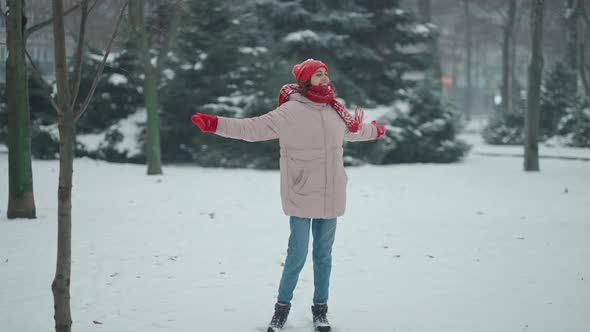 Happy Laughing Woman Walking and Playfully Running in Park at Snowfall Time