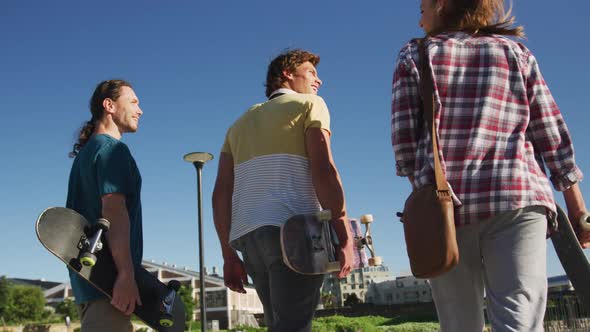 Back view of happy caucasian woman and two male friends spending time together on sunny day