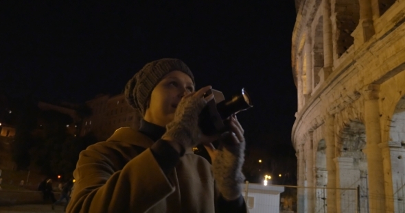 Woman With Retro Camera Shooting Coliseum At Night