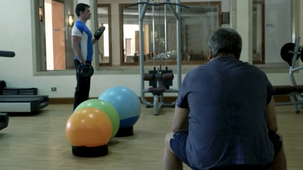 Man Exercising With Weight Disks, His Friend