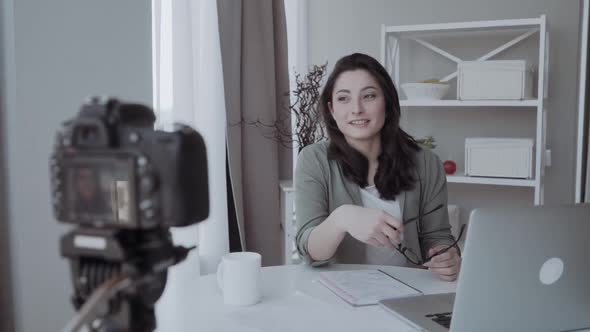 Young Woman Recording Video for Her Blog on a Digital Camera Mounted on Flexible Tripod. Smiling