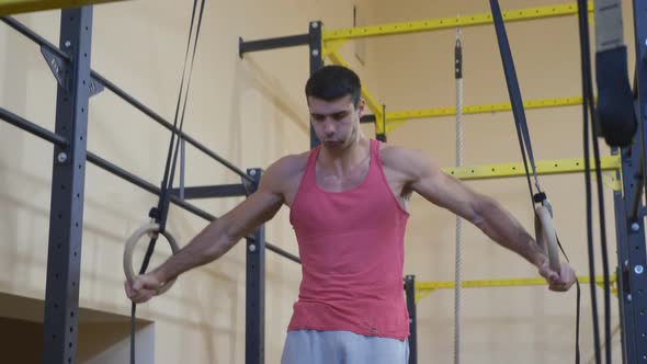 Muscular Sportsman Doing Cross on Gymnastic Rings at Gym