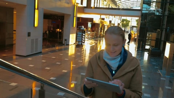 Woman Using Pad On The Stairs In Shopping Centre