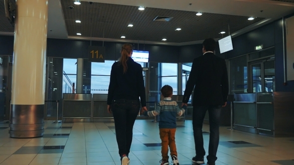 Family Of Three Walking In Airport Terminal