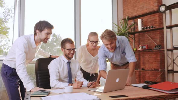 Three Succesful Businessmen and Businesswoman Discussing New Project Standing Around Table with