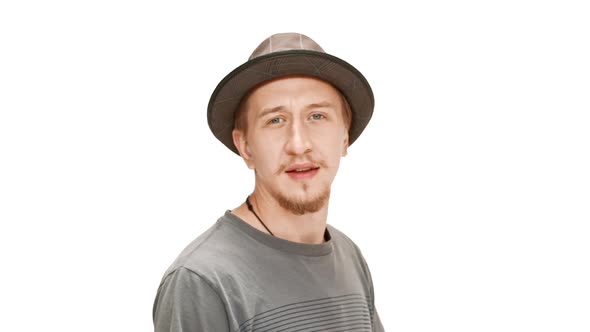 Displeased Young Handsome Man in Hat Passing By Over White Background