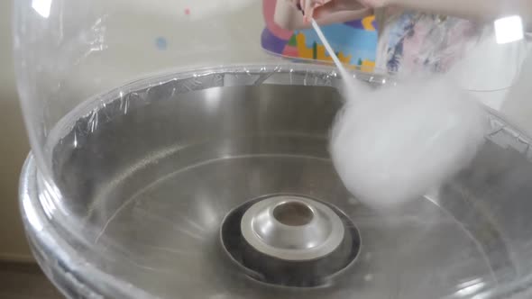 Female Hand Rolling Cotton Candy in Candy Floss Machine