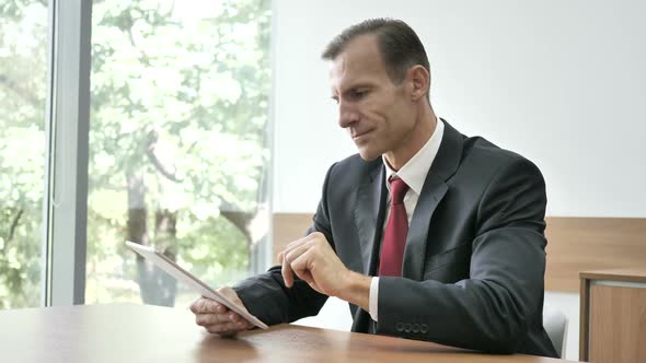 Businessman Cheering for Success While Using Tablet