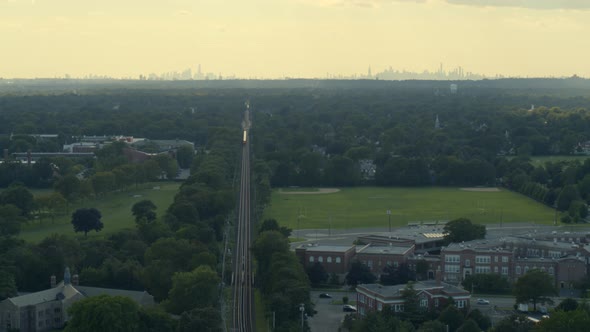 Aerial of a Train Passing Through Garden City and NYC Skyline Seen From Afar