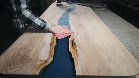 The Carpenter in the Workshop Wipes the Polished Countertop From Dust