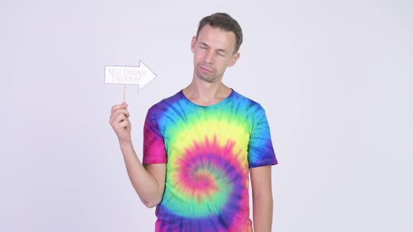 Frustrated Man with Tie-dye Shirt Holding Paper Sign and Giving Thumbs Down