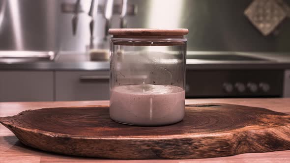 Sourdough Starter - Mixture Of Wild Yeast, Flour And Water Rising On Glass Jar With Wooden Lid Durin