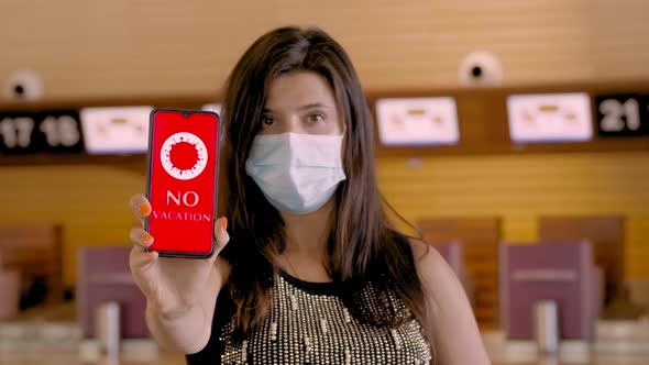 Woman, in Protective Mask, Holds Smartphone with COVID-19 Icon, Text - No Vacation, on Screen