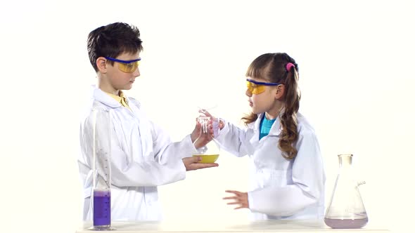 Two Cute Children in Protactive Glasses and Uniform Making Chemical Experiments, Mixing It and