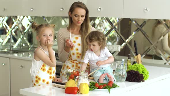 Young Mother With Children Cooking Healthy Food At Kitchen