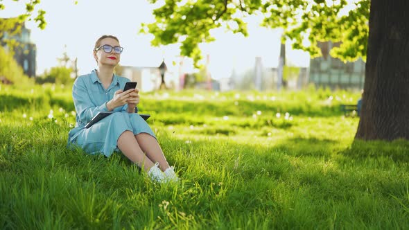 Woman Using Smartphone While Sitting in Park After Finishing Outdoor Work