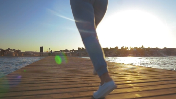 Woman Running On Wooden Pier At Sunset