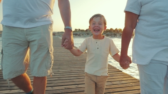 Happy Boy Walking With Grandparents Along The Pier alt