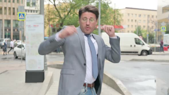 Middle Aged Businessman Dancing in Joy while Walking on Street