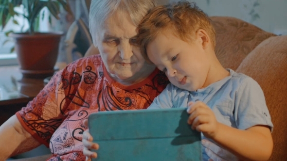 Grandmother And Grandson Use Tablet At Home
