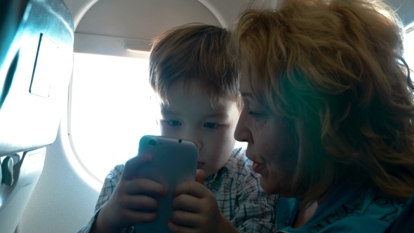 Grandmother And Grandson With Cell In The Plane alt