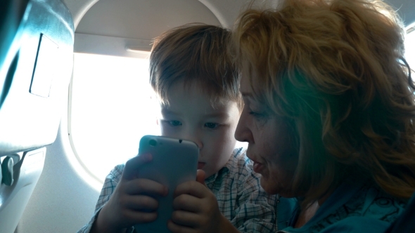 Grandmother And Grandson With Cell In The Plane