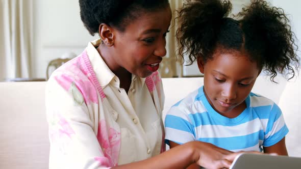 Mother and daughter using laptop in living room