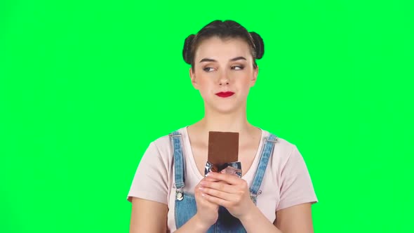 Girl with Great Pleasure Eats Chocolate on a Green Screen in the Studio, Slow Motion