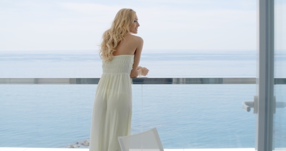 Woman Leaning On Ocean Front Balcony Railing
