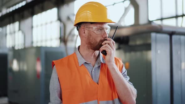 Serious man engineer in uniform talking into walkie-talkie