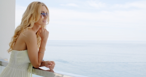 Woman Enjoying View Of Ocean From Balcony