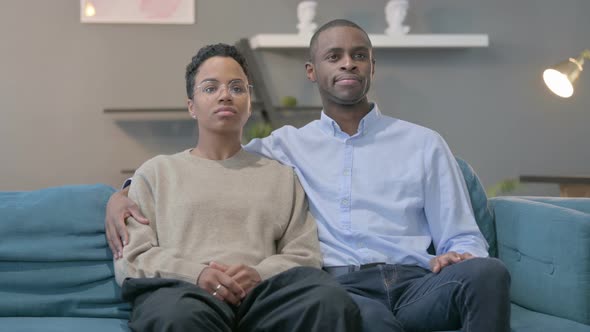 Couple Smiling at Camera While Sitting on Sofa