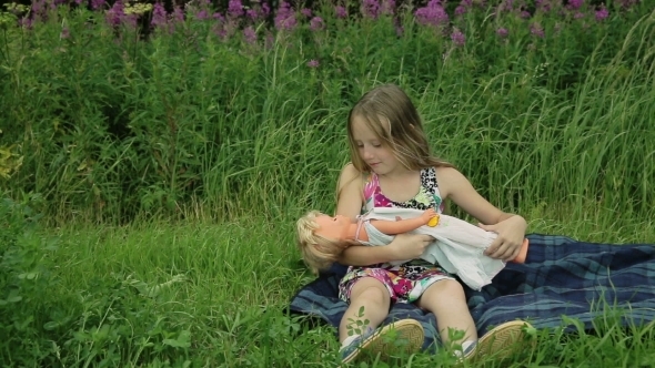 Young Girl Playing With Doll On Outside Grass