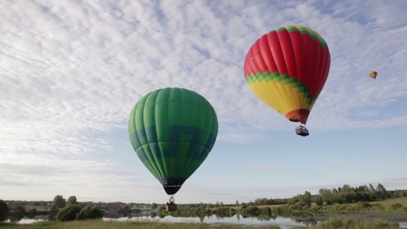 Hot Air Balloons Flying Over Lake And Field
