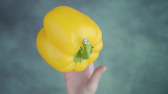 Person Hand Throwing Up Bell Pepper Above Table Surface