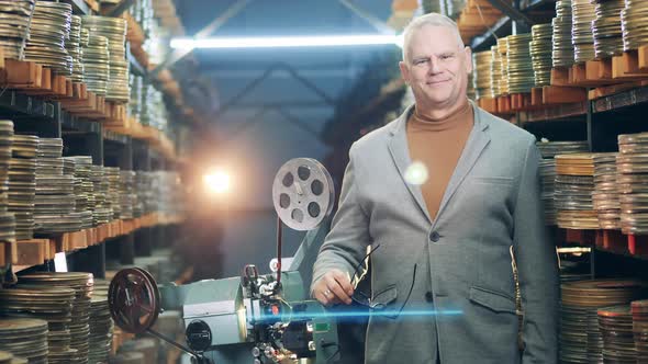 Vintage Film Projector with a Smiling Archivist Standing Near