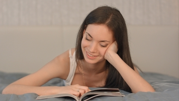 The Girl Reads The Magazine Lying On a Bed.