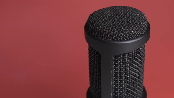 Studio Condenser Microphone Rotates on Red Background with Place for Text