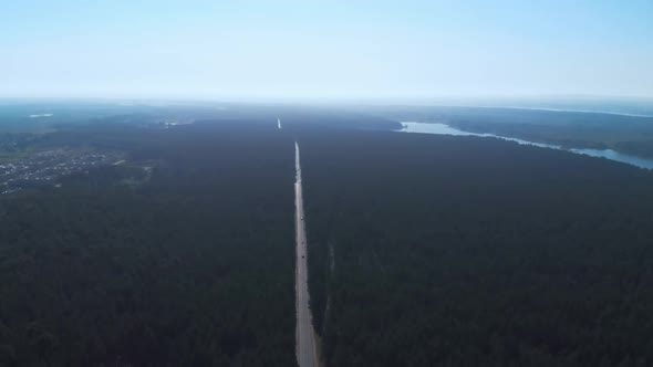 Drone Shot From Sky Height Showing Cars on Highway Passing Frough Massive Green Pine Forest