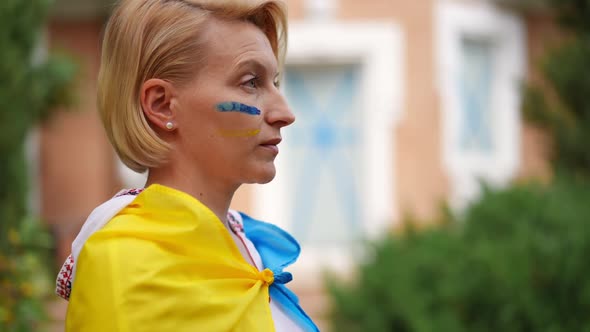 Side View Adult Woman in Embroidered Shirt and Ukrainian Flag Looking Away Standing on the Left