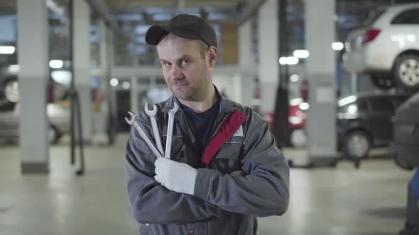 Portrait of Adult Caucasian Man in Workwear Standing in Repair Shop with Adjustable Wrenches and