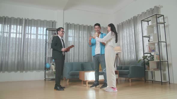 Full View Of Asian Couple Receiving The House Model From A Real Estate Agent In The House For Sale