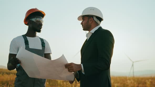 Close Up Face Two Professionals Technicians in Hard Hat Using a Large Blueprint