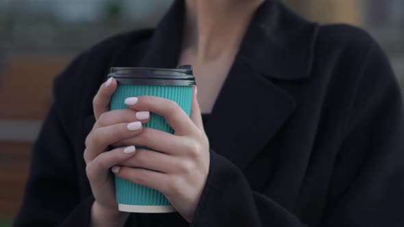 Female Hands Hold a Cup of Beverage on a Street